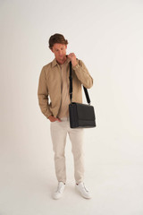 Profile view of model wearing the Oroton Weston Satchel in Black and Pebble Leather for Men