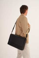 Profile view of model wearing the Oroton Weston Satchel in Black and Pebble Leather for Men