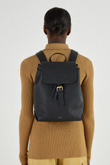 Profile view of model wearing the Oroton Margot Medium Backpack in Black and Pebble Leather for Women