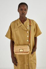 Profile view of model wearing the Oroton Kerr Collectable Small Day Bag in Natural/Brandy and Raffia for Women