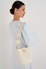Profile view of model wearing the Oroton Logo Bag Strap in Ecru/Cream and Smooth Leather And Webbing for Women