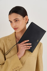 Profile view of model wearing the Oroton Muse Medium Pouch in Black and Saffiano And Smooth Leather for Women