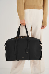 Profile view of model wearing the Oroton Margot Weekender in Black and Pebble Leather for Women