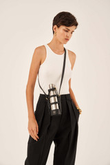 Profile view of model wearing the Oroton Margot Bottle Holder Crossbody in Black and Pebble Leather for Women