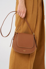 Profile view of model wearing the Oroton Margot Saddle Crossbody in Whiskey and Pebble Leather for Women