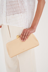 Profile view of model wearing the Oroton Nova Clutch in Creamed Honey and Smooth Leather for Women