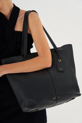 Profile view of model wearing the Oroton Lilly Shopper Tote in Black and Pebble Leather for Women