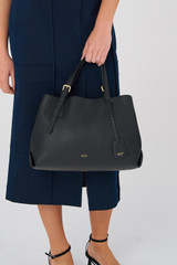 Profile view of model wearing the Oroton Margot Medium Day Bag in Black and Pebble Leather for Women