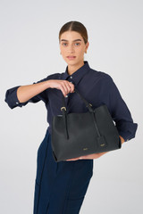Profile view of model wearing the Oroton Margot Medium Day Bag in Black and Pebble Leather for Women