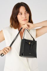 Profile view of model wearing the Oroton Margot Tiny Bucket Bag in Black and Pebble leather for 