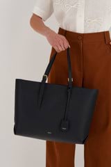 Profile view of model wearing the Oroton Margot Medium Zip Tote in Black and Pebble Leather for Women
