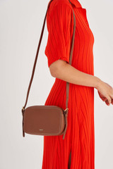 Profile view of model wearing the Oroton Margot Zip Around Crossbody in Whiskey and Pebble leather for Women