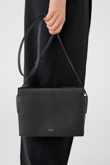 Profile view of model wearing the Oroton Margot Zip Crossbody in Black and Pebble Leather for Women