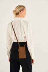 Profile view of model wearing the Oroton Lilly Phone Crossbody in Cognac and Pebble Leather for Women