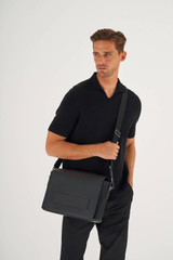 Profile view of model wearing the Oroton Liam Satchel in Black and Smooth Leather for Men