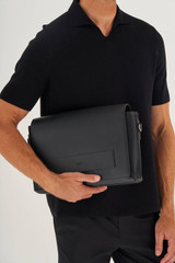 Profile view of model wearing the Oroton Liam Satchel in Black and Smooth Leather for Men