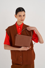 Profile view of model wearing the Oroton Margot Zip Crossbody in Whiskey and Pebble Leather for Women