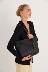 Profile view of model wearing the Oroton Lilly Small Shopper Tote in Black and Pebble Leather for Women