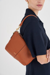 Profile view of model wearing the Oroton Lilly Zip Top Hobo in Cognac and Pebble leather for Women