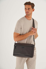 Profile view of model wearing the Oroton Lucas 13" Satchel in Chocolate/Black and Pebble Leather for Men
