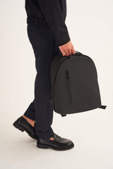 Profile view of model wearing the Oroton Larsen Backpack in Black and Coated Canvas for Men