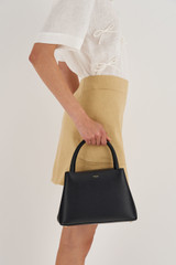 Profile view of model wearing the Oroton Muse Small Day Bag in Black and Saffiano / Smooth Leather for Women
