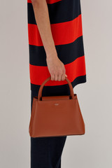Profile view of model wearing the Oroton Muse Small Day Bag in Cognac and Saffiano / Smooth Leather for Women