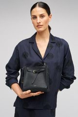 Profile view of model wearing the Oroton Margot Mini Bucket Bag in Black and Pebble leather for Women