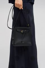 Profile view of model wearing the Oroton Margot Mini Bucket Bag in Black and Pebble leather for Women