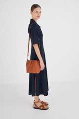 Profile view of model wearing the Oroton Lilly Small Bucket Bag in Cognac and Pebble Leather for Women