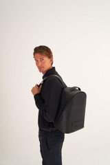 Profile view of model wearing the Oroton Liam Backpack in Black and Smooth Leather for Men