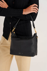 Profile view of model wearing the Oroton Lilly Zip Top Hobo in Black and Pebble leather for Women