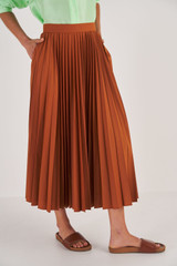 Profile view of model wearing the Oroton Pleat Skirt in Brandy and 65% Polyester, 35% Cotton for Women