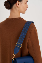 Profile view of model wearing the Oroton Logo Bag Strap in Fisherman Blue and Logo Jacquard Webbing With Leather Trims for Women