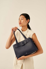 Profile view of model wearing the Oroton Avery Three Pocket Day Bag in Denim Blue and Soft Pebble Leather for Women