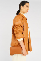 Profile view of model wearing the Oroton Inez Chain Crossbody in Cognac and Shiny Soft Saffiano for Women