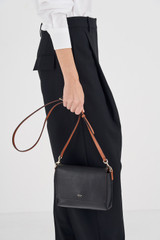 Profile view of model wearing the Oroton Harriet Crossbody in Black and Saffiano Leather With Smooth Leather Trim for Women