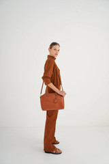 Profile view of model wearing the Oroton Inez Day Bag in Cognac and Shiny Soft Saffiano for Women