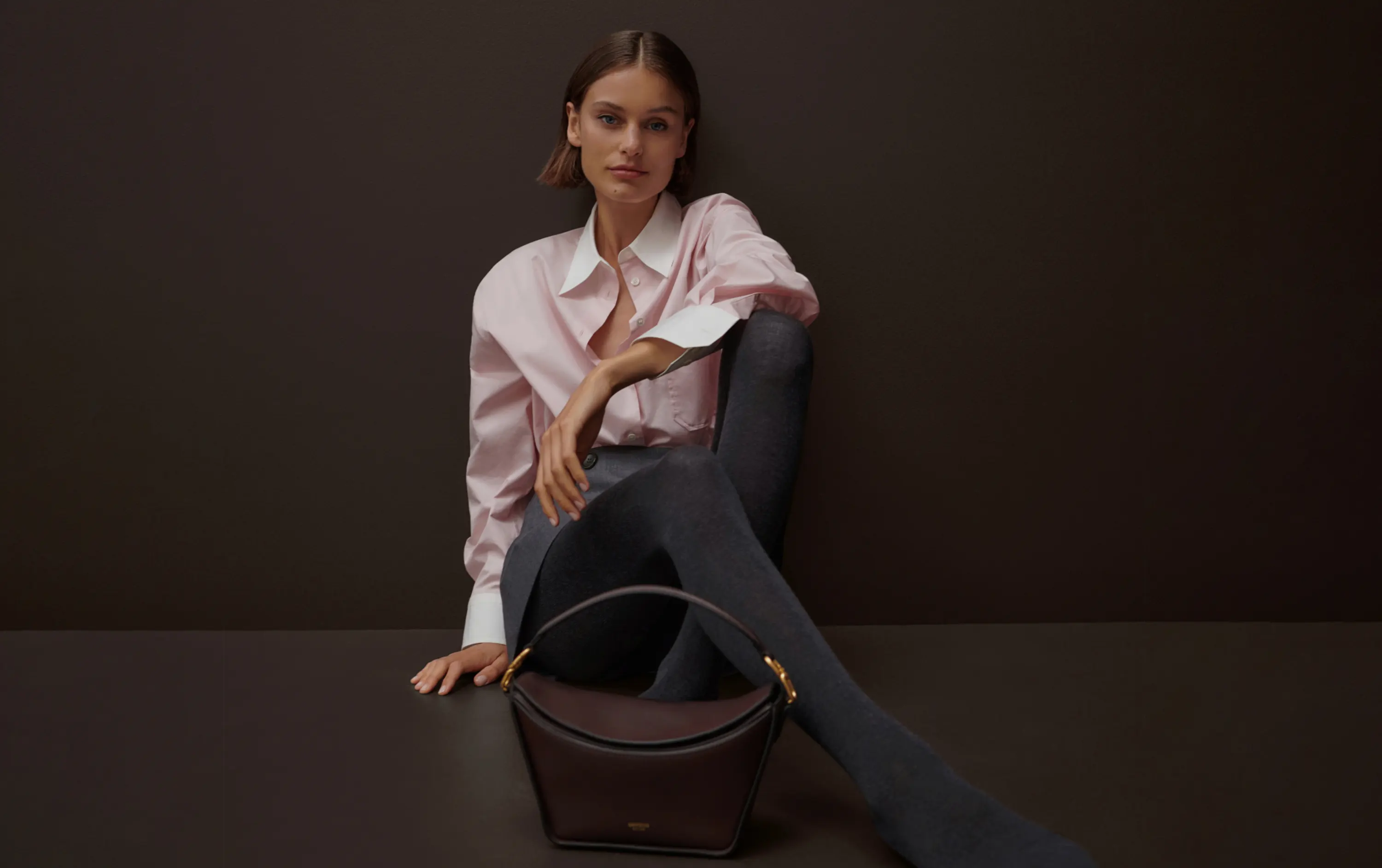 Model in pink collared Oroton shirt with brown leather handbag
