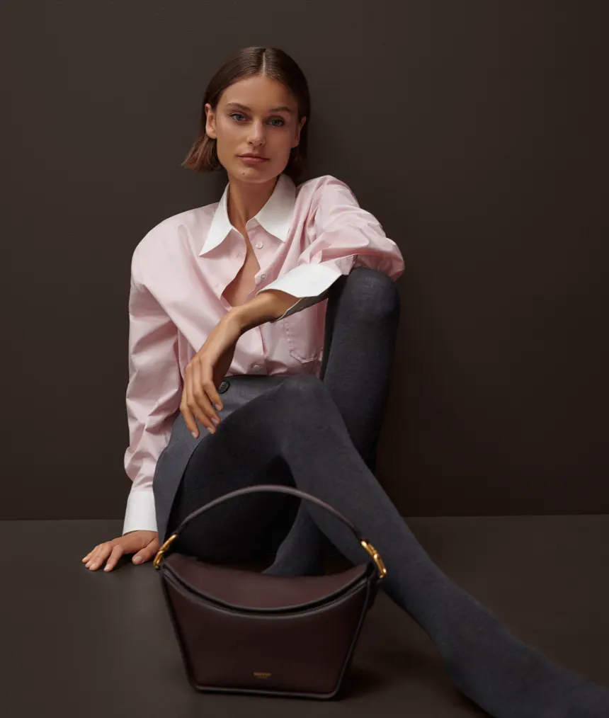 Woman wearing pink collared shirt with brown Oroton handbag